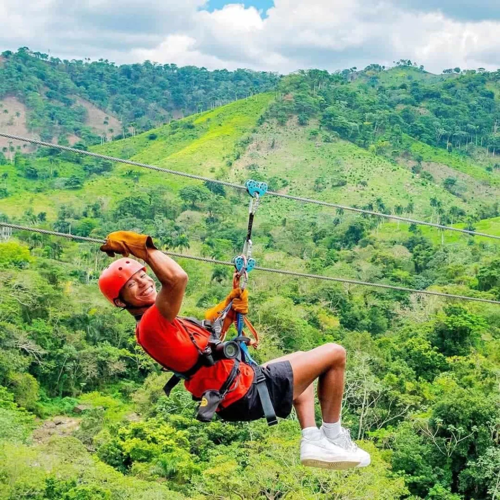 Man zip-lining through lush greenery in Miches, enjoying an adventurous outdoor activity.