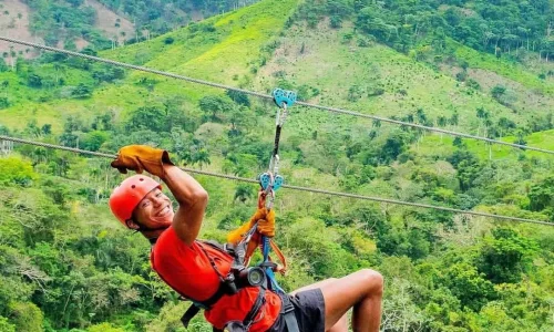 Man zip-lining through lush greenery in Miches, enjoying an adventurous outdoor activity.