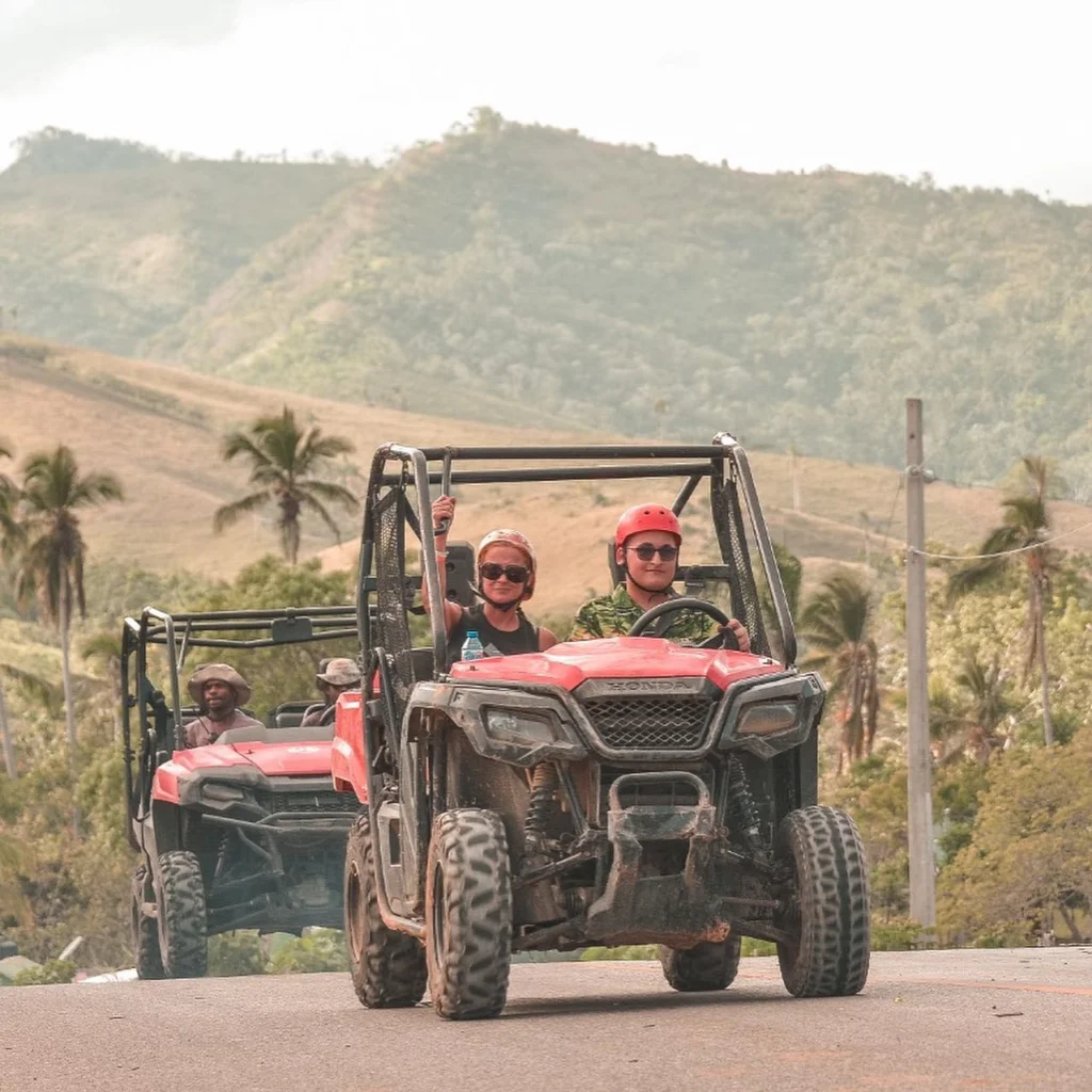Excited tourists driving ATVs through scenic Miches hills, ready for adventure and exploration.