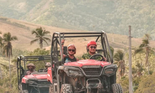 Excited tourists driving ATVs through scenic Miches hills, ready for adventure and exploration.